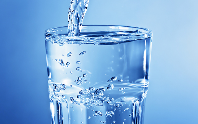 Ein Wasserglas wird mit Wasser befüllt Ein Wasserglas wird mit Wasser befüllt