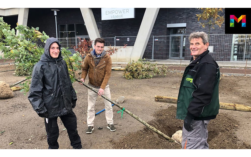 Drei Menschen an einer Baustelle, einer am Buddeln