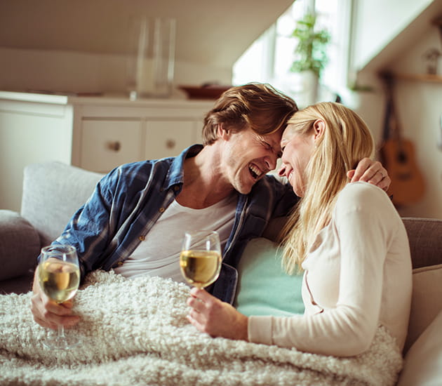 Paar sitzt mit Weingläsern auf dem Sofa