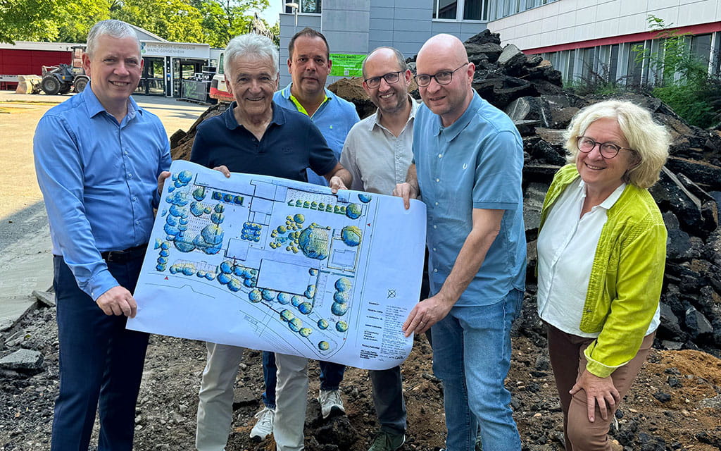 Personengruppe mit einem Begrünungsplan vor einer Baustelle