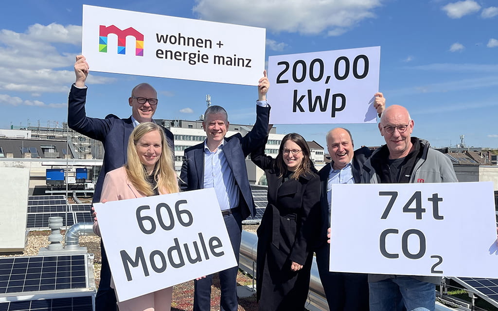 Personen stehen auf einem Hausdach und halten Schilder zu PV-Anlagen hoch