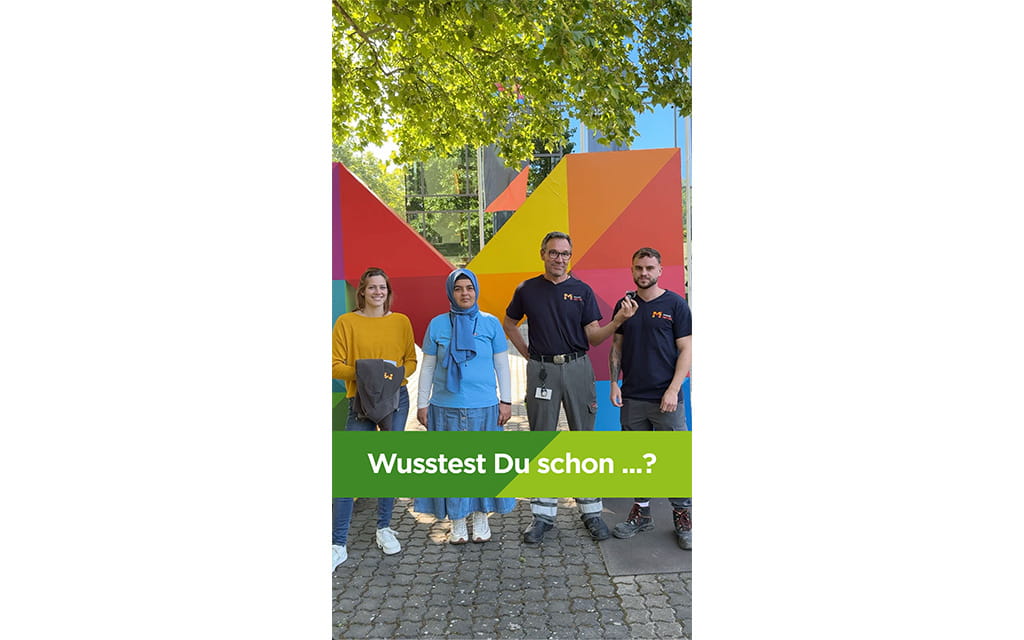 Wusstest du schon Titelbild, drei Menschen vor dem bunten M