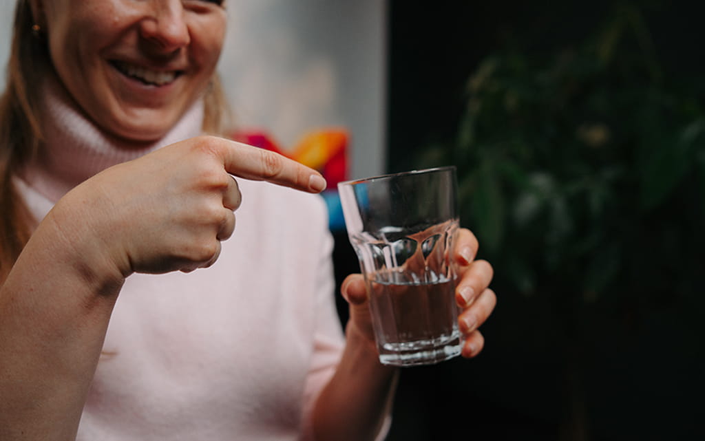 Frau zeigt mit dem Finger auf ein Glas Wasser