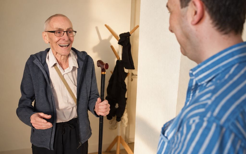 Ein Mann bringt einem älterer Mann seinen Gehstock zurück