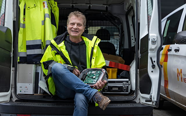Monteur der Mainzer Netze sitzt in der Ladefläche eines Transporters und hält ein Gerät mit Platine in der Hand