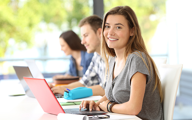 Schülerin sitzt mit einem Laptop im Klassenraum Schülerin sitzt mit einem Laptop im Klassenraum